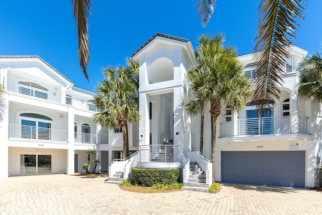 view of front of property featuring a garage, a tiled roof, decorative driveway, and stucco siding