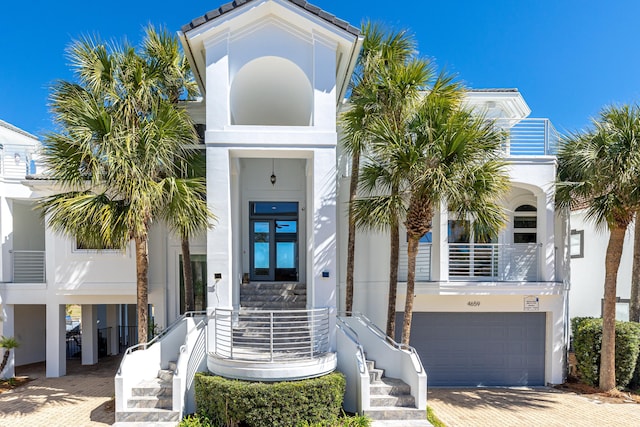 exterior space with an attached garage, french doors, decorative driveway, and stucco siding