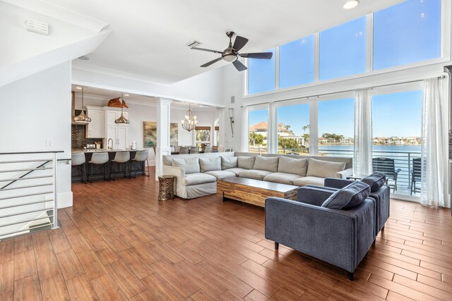 living room with recessed lighting, a water view, visible vents, wood finished floors, and ceiling fan with notable chandelier