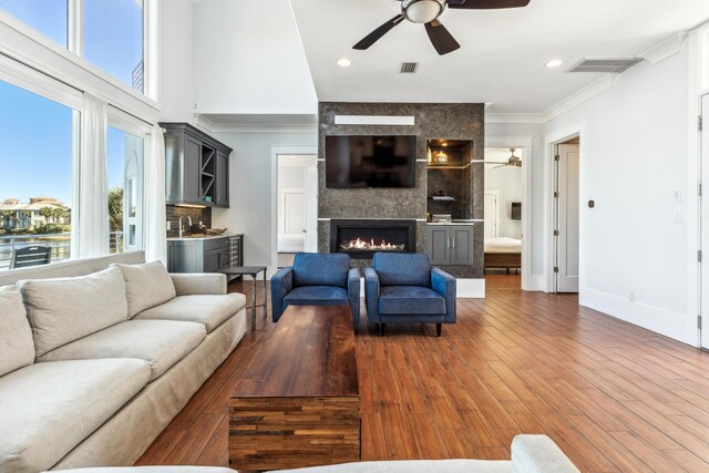 living room featuring a large fireplace, wood finished floors, visible vents, and a healthy amount of sunlight