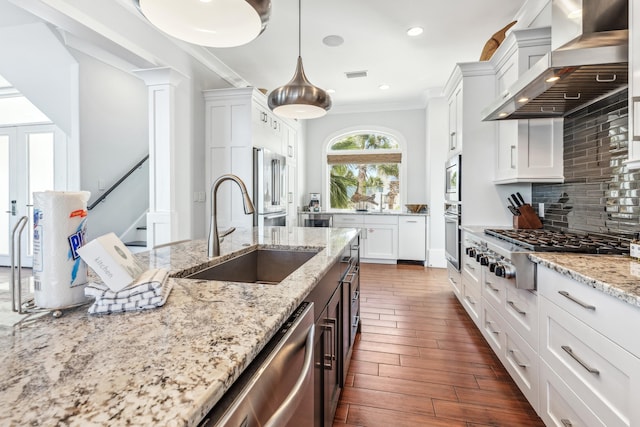 kitchen with tasteful backsplash, visible vents, wall chimney exhaust hood, stainless steel appliances, and a sink