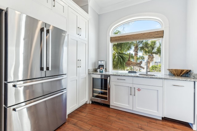 kitchen featuring beverage cooler, dark wood-style flooring, white cabinets, freestanding refrigerator, and light stone countertops