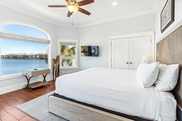 bedroom featuring ornamental molding, a ceiling fan, baseboards, and wood finished floors