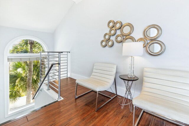 sitting room with lofted ceiling, hardwood / wood-style floors, an upstairs landing, and baseboards