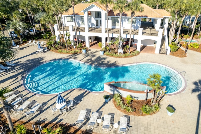 community pool with a patio area and a hot tub