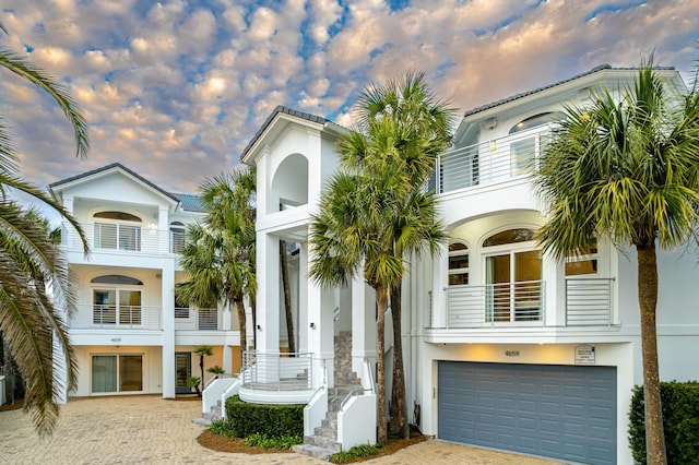 view of front of home with stucco siding, driveway, an attached garage, and a balcony