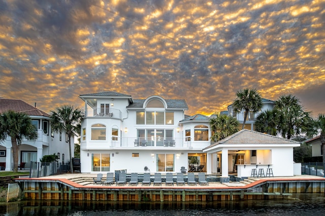 4659 Destiny Way, Destin, FL 32541 - back of property at dusk with stucco siding, a water view, a balcony, and a patio area