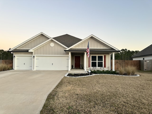 view of front of house with board and batten siding, fence, a garage, driveway, and a front lawn