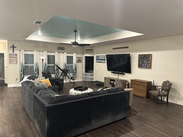 living area featuring a ceiling fan, a raised ceiling, visible vents, and dark wood-style flooring