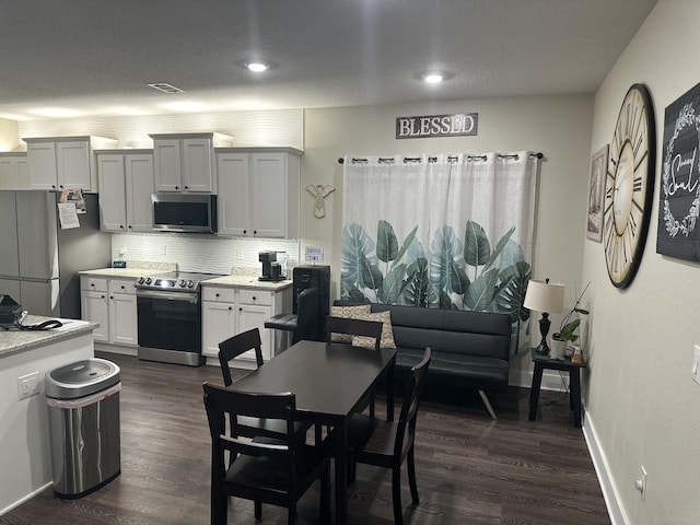kitchen featuring dark wood-style flooring, white cabinetry, light countertops, appliances with stainless steel finishes, and tasteful backsplash