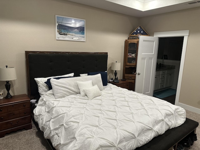 carpeted bedroom featuring ensuite bath and baseboards
