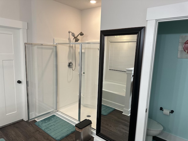 full bathroom featuring a stall shower, a garden tub, toilet, and wood finished floors