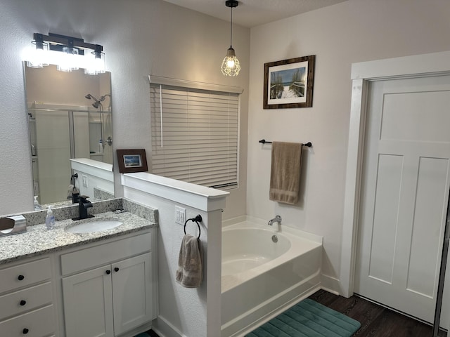 bathroom with a textured wall, wood finished floors, a shower with shower door, vanity, and a bath