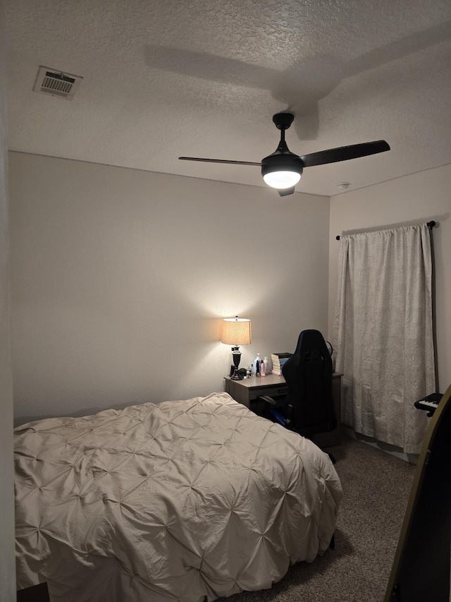 bedroom with a ceiling fan, carpet, visible vents, and a textured ceiling