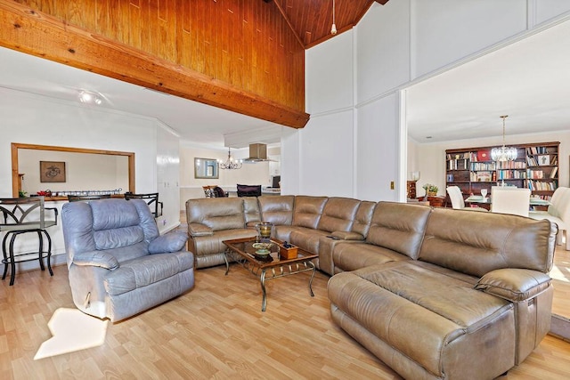 living area with a chandelier, light wood-style floors, a towering ceiling, and beamed ceiling