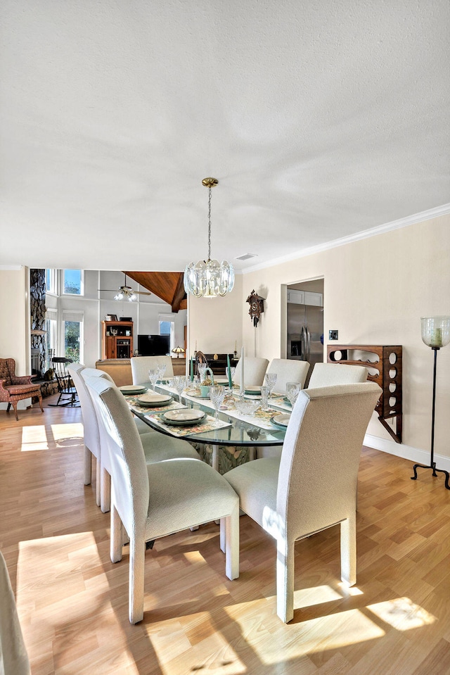 dining room with light wood finished floors, baseboards, ornamental molding, vaulted ceiling, and a notable chandelier