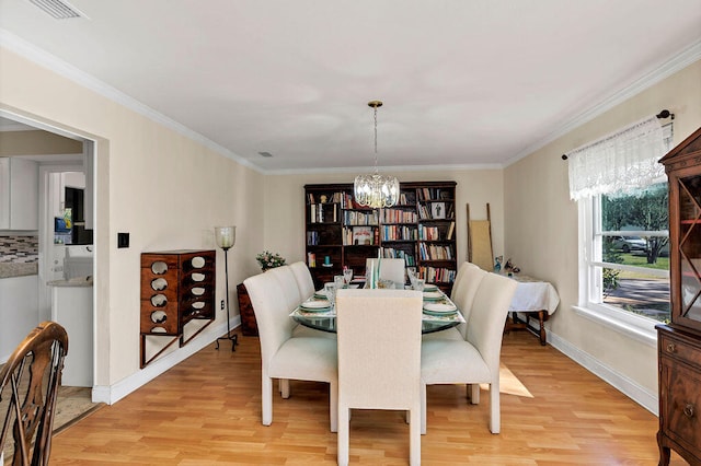 dining area with ornamental molding, visible vents, a notable chandelier, and light wood finished floors