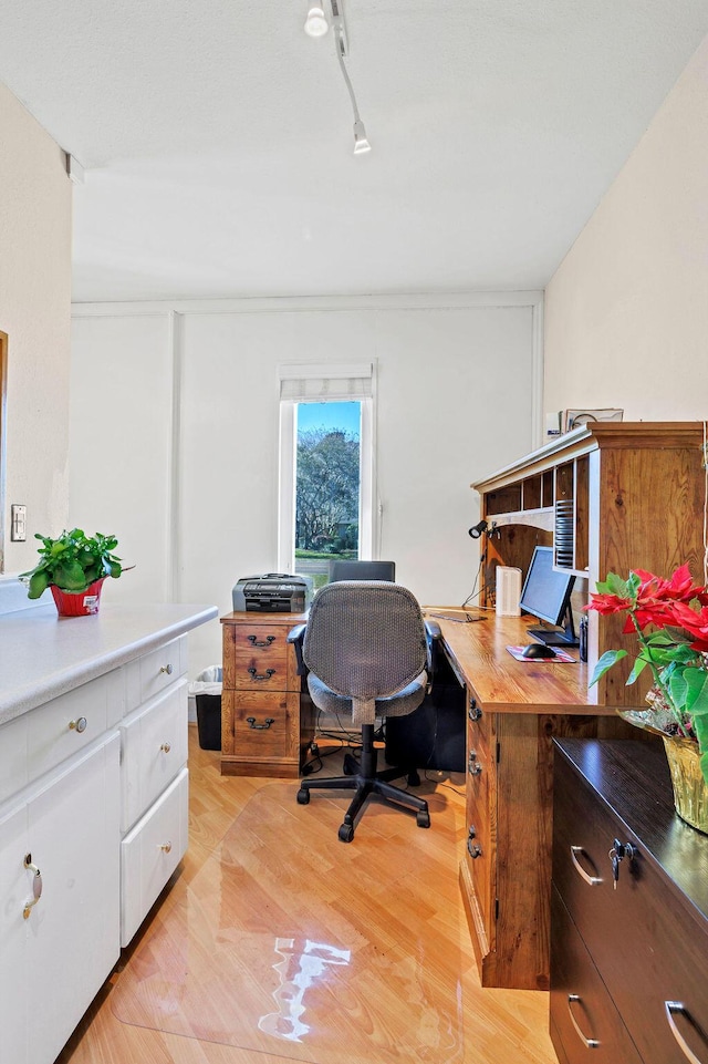 home office with light wood-style flooring and track lighting