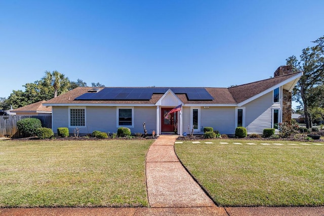 view of front facade featuring a front yard, fence, and solar panels