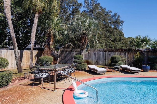 view of swimming pool with a fenced in pool, outdoor dining space, a fenced backyard, and a patio