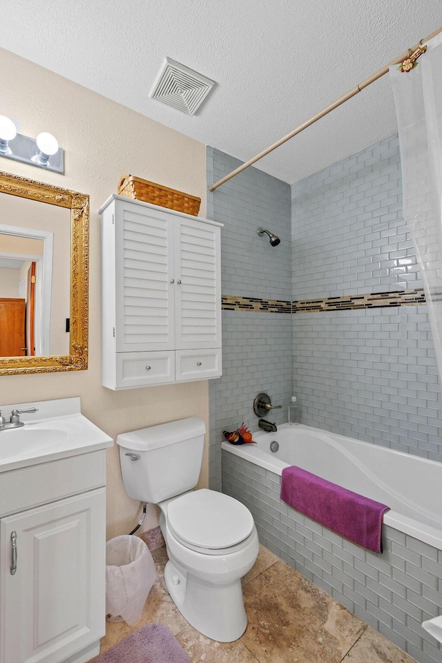 bathroom with a textured ceiling, toilet, tiled shower / bath combo, vanity, and visible vents