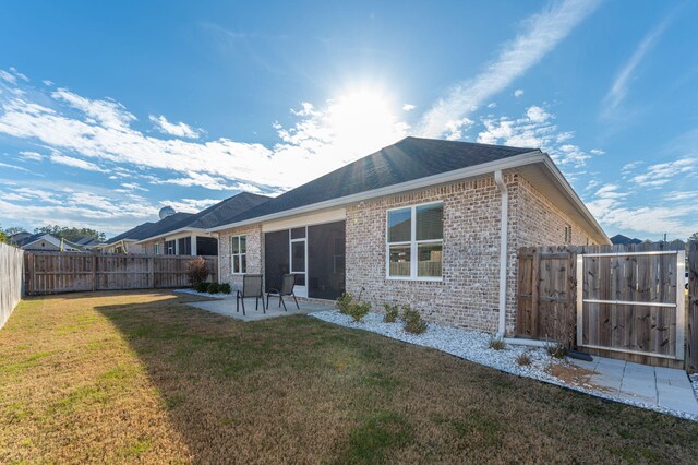 back of property with a patio area, a fenced backyard, a lawn, and brick siding