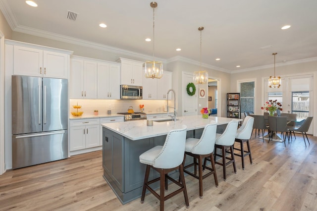 kitchen featuring light wood finished floors, tasteful backsplash, visible vents, white cabinets, and appliances with stainless steel finishes