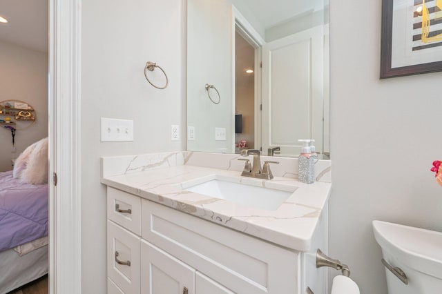 ensuite bathroom with toilet, connected bathroom, and vanity