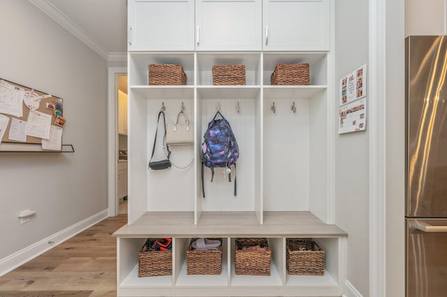 mudroom featuring light wood-style floors, crown molding, and baseboards