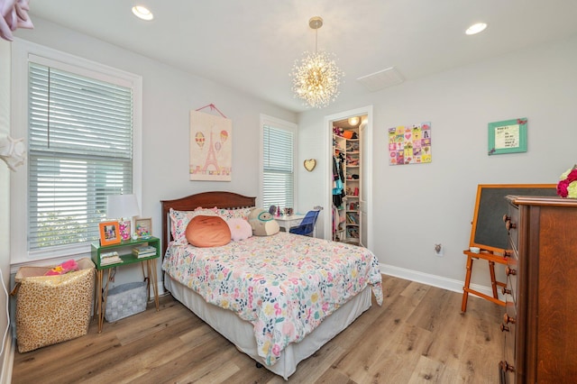 bedroom featuring a chandelier, recessed lighting, baseboards, a spacious closet, and light wood finished floors