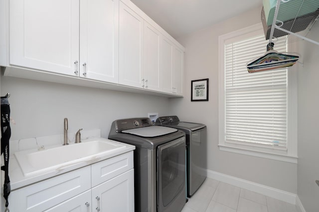 clothes washing area featuring light tile patterned floors, cabinet space, a sink, independent washer and dryer, and baseboards