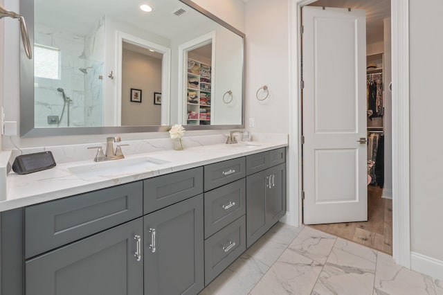 full bath with a sink, visible vents, marble finish floor, a marble finish shower, and double vanity