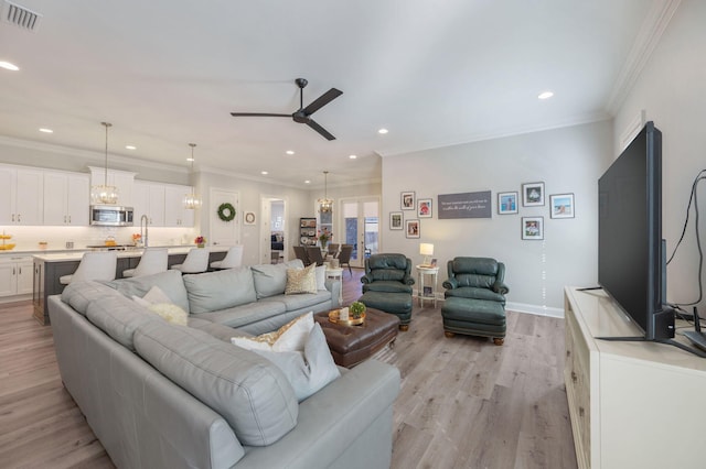 living area featuring light wood-style floors, recessed lighting, visible vents, and ornamental molding