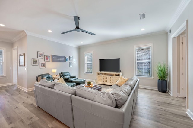 living room featuring light wood finished floors, plenty of natural light, and crown molding