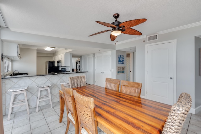 dining area featuring a textured ceiling, light tile patterned floors, a ceiling fan, visible vents, and crown molding