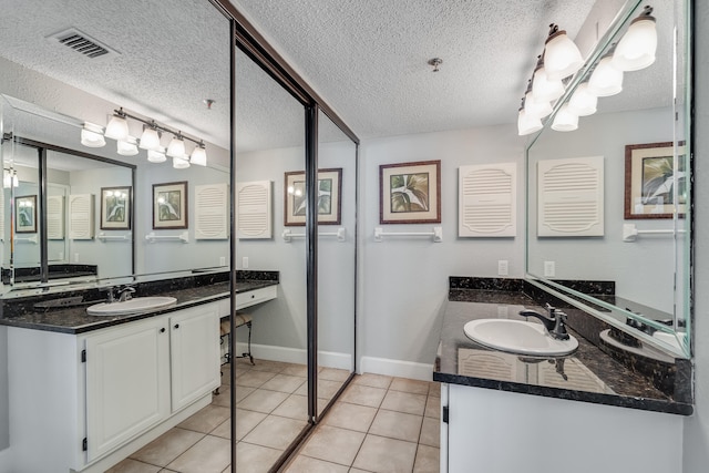 full bath with two vanities, tile patterned flooring, visible vents, and a sink