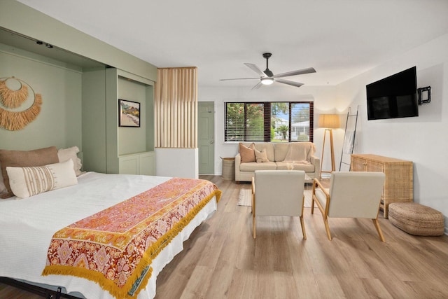 bedroom featuring a ceiling fan, wainscoting, and wood finished floors