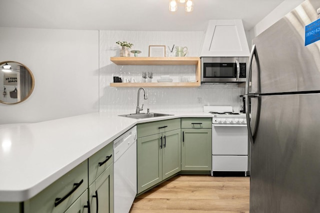 kitchen with stainless steel appliances, light countertops, backsplash, green cabinets, and a sink