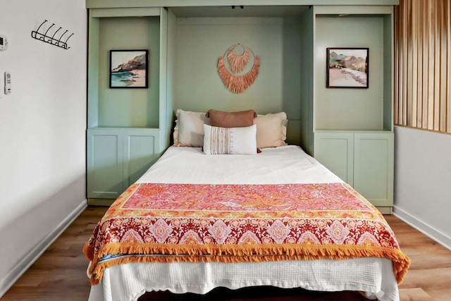 bedroom with a wainscoted wall and wood finished floors