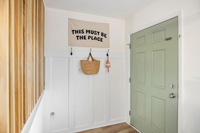 mudroom featuring a wainscoted wall, a decorative wall, and wood finished floors