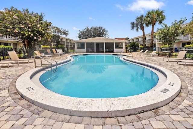 community pool with a patio, fence, and a sunroom