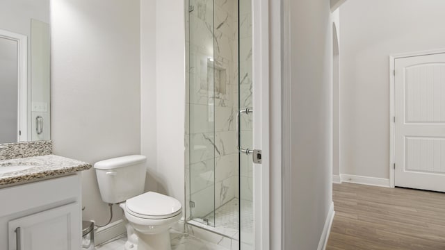 full bathroom featuring vanity, toilet, baseboards, and a marble finish shower