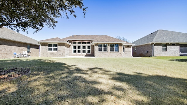 back of house featuring brick siding and a yard
