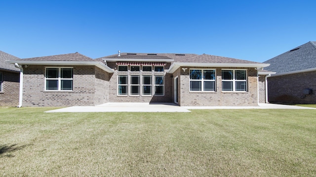 back of house featuring a lawn, brick siding, and a patio