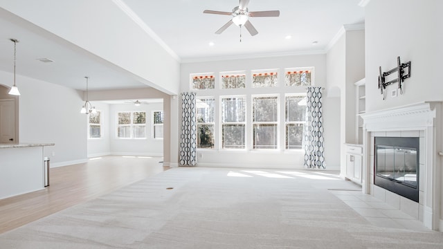 unfurnished living room with a tiled fireplace, crown molding, and ceiling fan