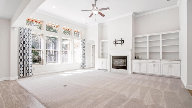 unfurnished living room featuring a fireplace, crown molding, a ceiling fan, and baseboards
