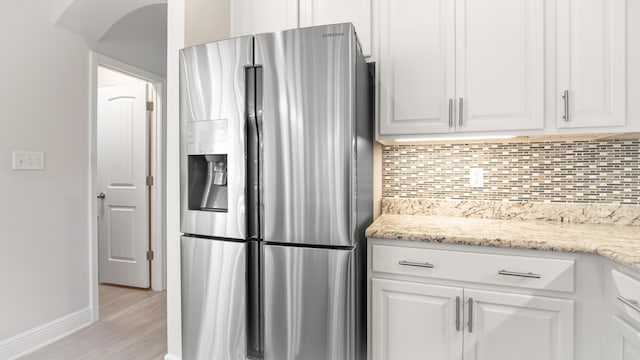 kitchen with decorative backsplash, light wood-style flooring, baseboards, white cabinets, and stainless steel refrigerator with ice dispenser