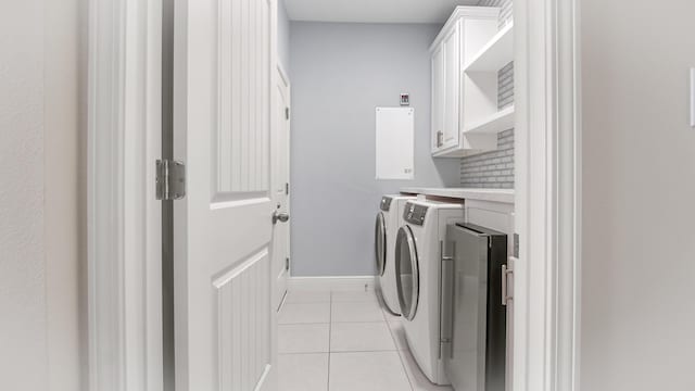 clothes washing area featuring washing machine and dryer, baseboards, light tile patterned floors, and cabinet space