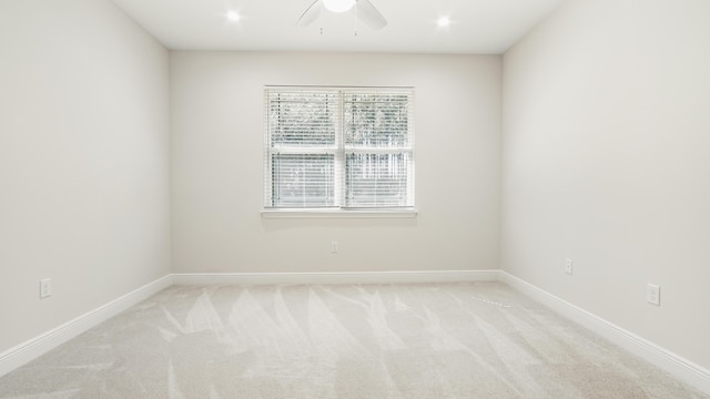 spare room featuring a ceiling fan, baseboards, and light carpet