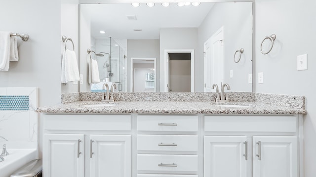 bathroom with a sink, double vanity, and a stall shower